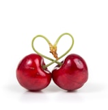 two red cherry fruits on white surface