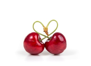 two red cherry fruits on white surface