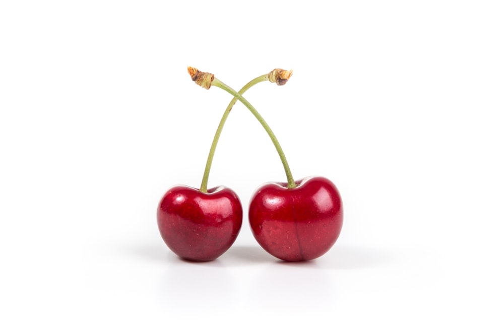two cherries on white surface