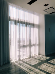 Bright standard room with natural light flowing through sheer curtains.