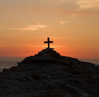 cross silhouette on mountain during golden hour