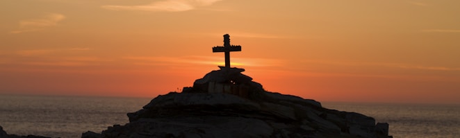 cross silhouette on mountain during golden hour