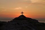 cross silhouette on mountain during golden hour