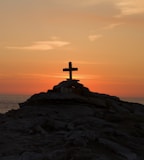 cross silhouette on mountain during golden hour