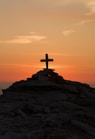 cross silhouette on mountain during golden hour