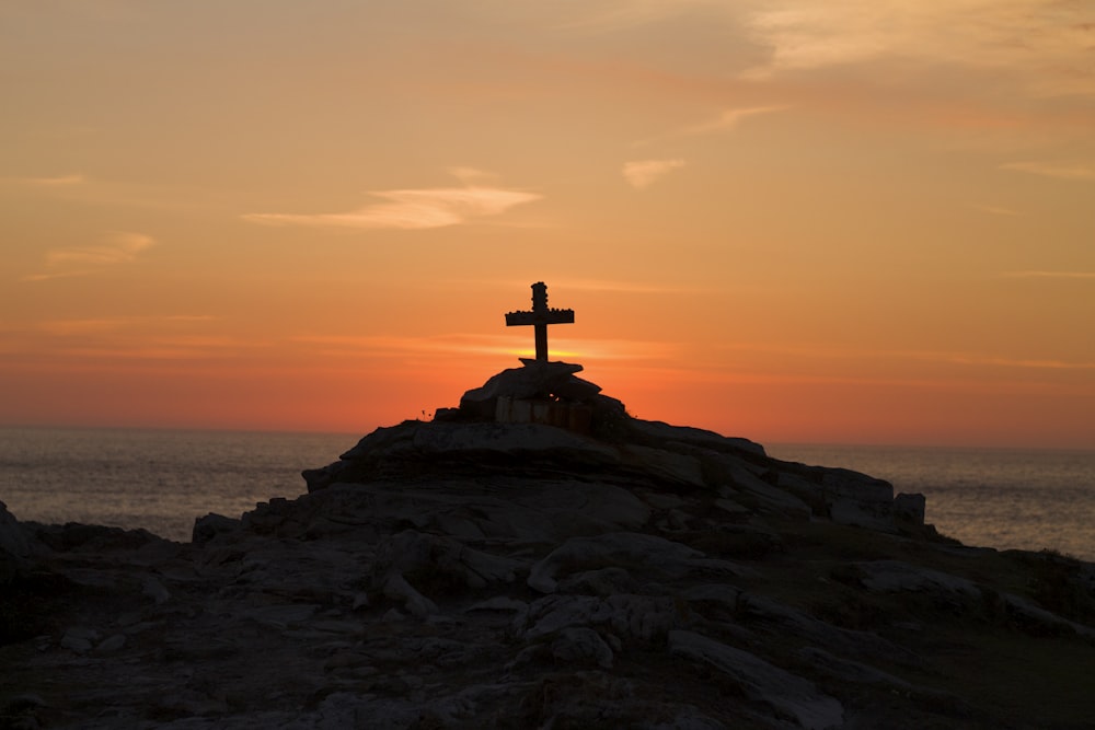 cross silhouette on mountain during golden hour