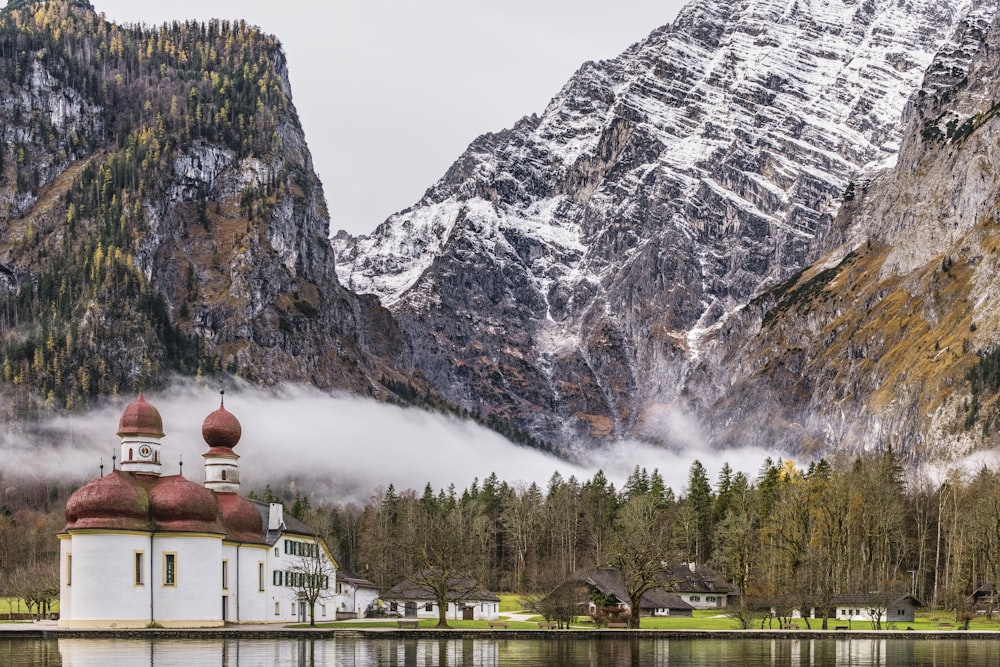 a church in the middle of a lake with mountains in the background