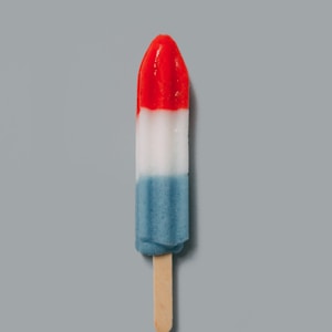 red, white, and blue popsicle on beige surface