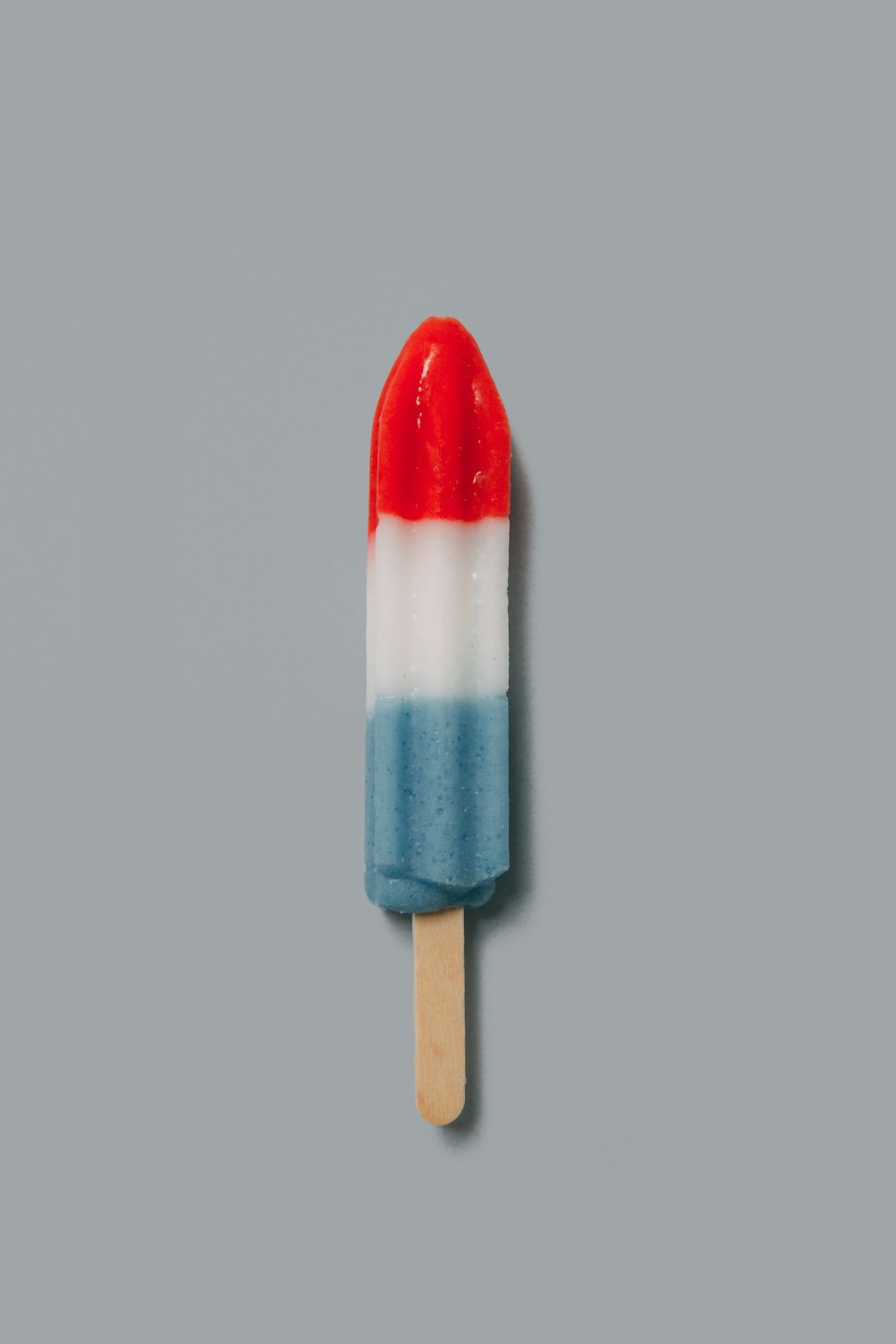 red, white, and blue popsicle on beige surface