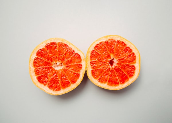 A sliced grapefruit in half resembling breasts.