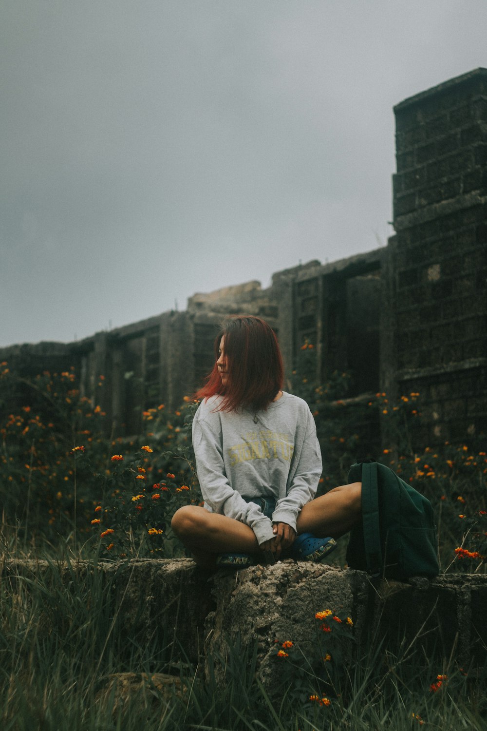 woman sitting on concrete fence