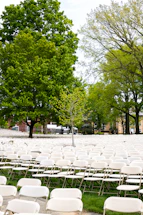 A neat row of foldable chairs set up outdoors under a bright sky.