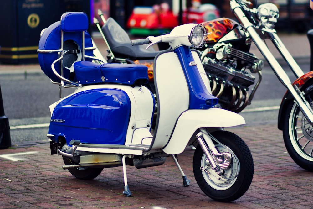 Estacionamento de scooter de motor branco e azul ao lado da motocicleta cruiser