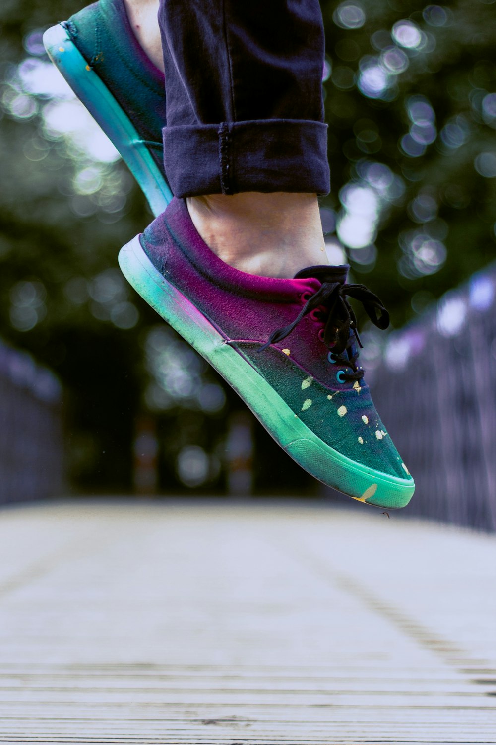 selective focus photography of person wearing multicolored sneakers while jumping