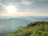 A panoramic view of lush green hills under a sunrise.