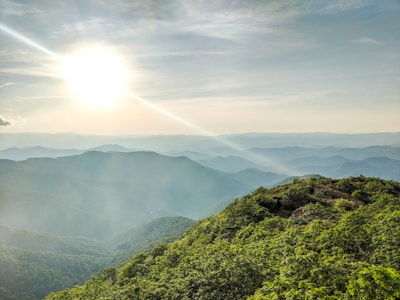 A panoramic view of lush green hills under a sunrise.