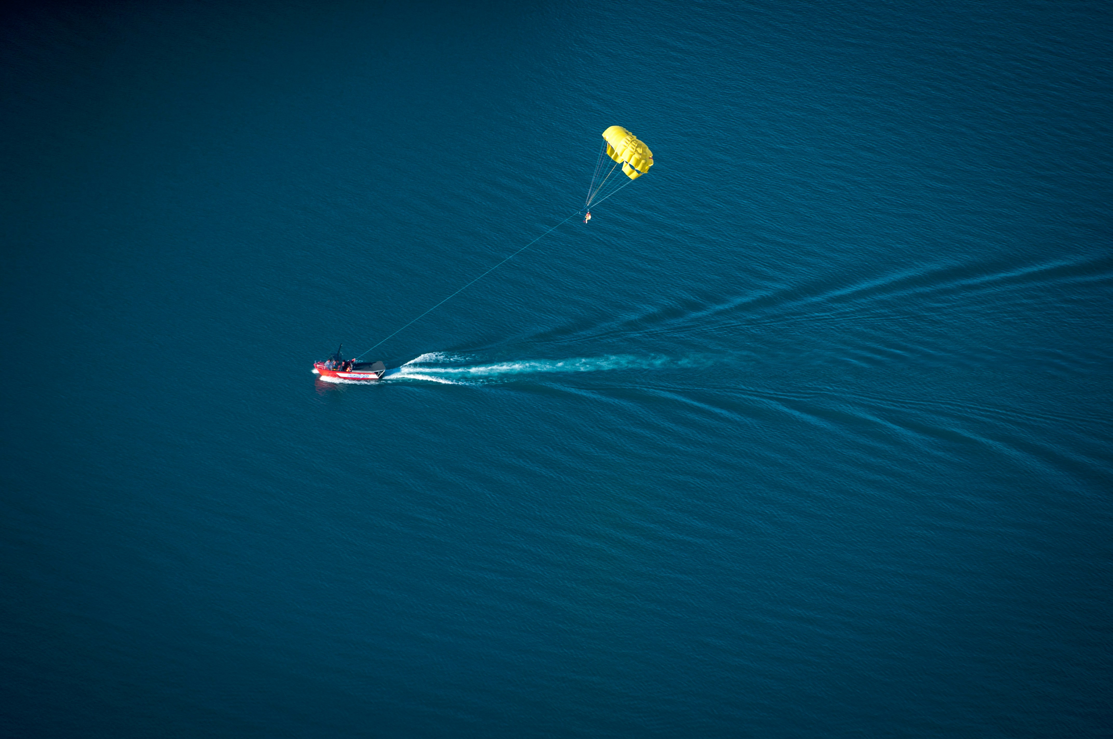parachute near red personal water craft