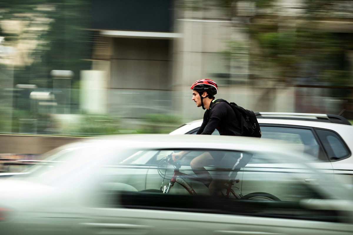 Trabajador yendo en bicicleta al trabajo entre autos en la ciudad