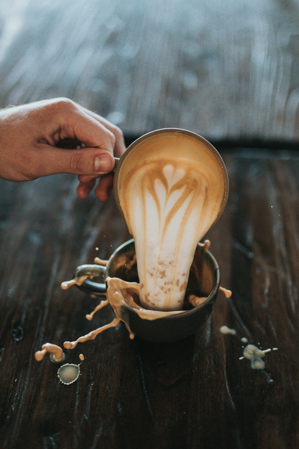 別のカップにカプチーノを注ぐ男