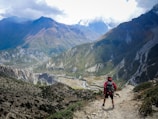 person in red top waling beside mountain