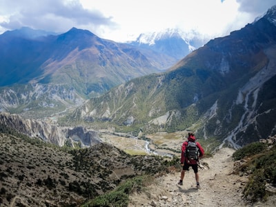 person in red top waling beside mountain