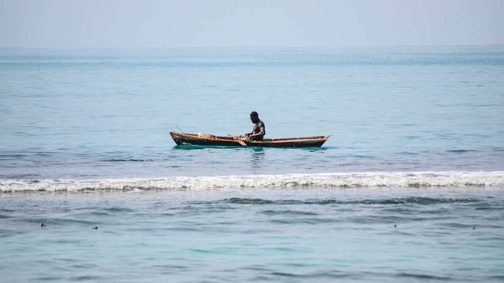 Mann reitet tagsüber auf braunem Boot auf dem Meer