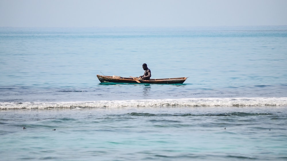 man riding on brown boat on sea during daytime