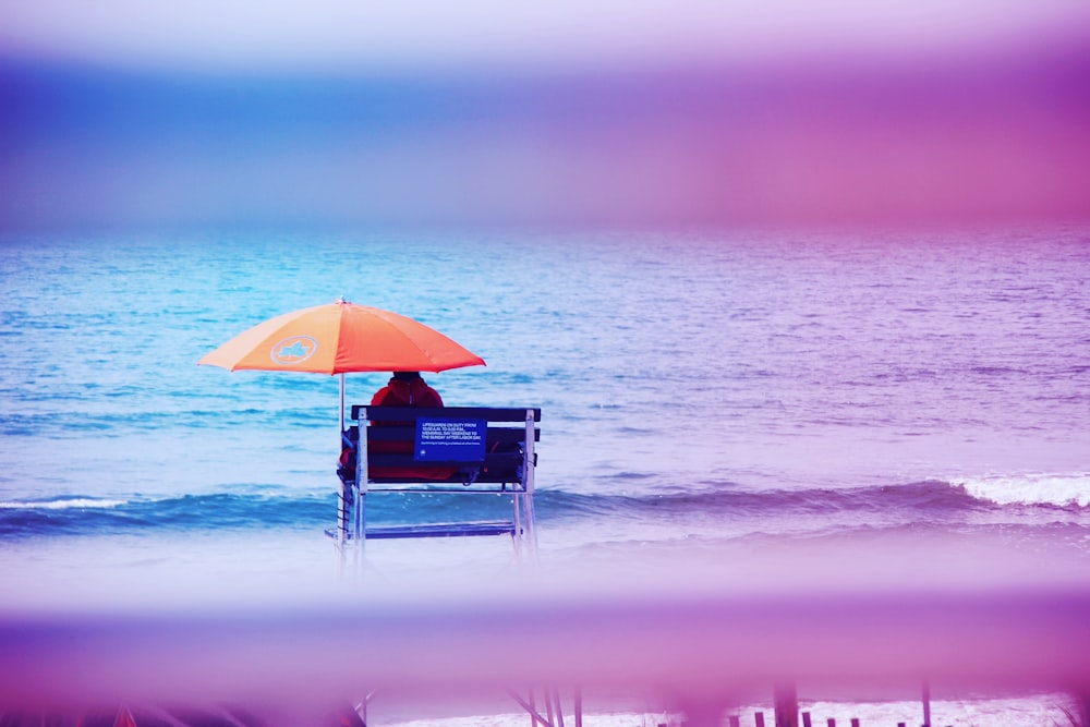 person sitting on lifeguard tower near shore