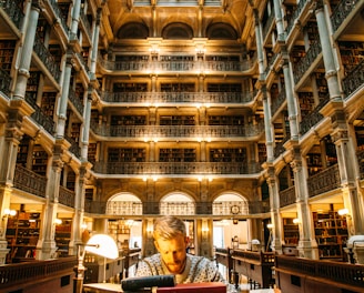 man sitting on chair near desk surrounded with books