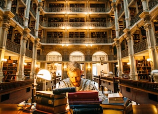 man sitting on chair near desk surrounded with books