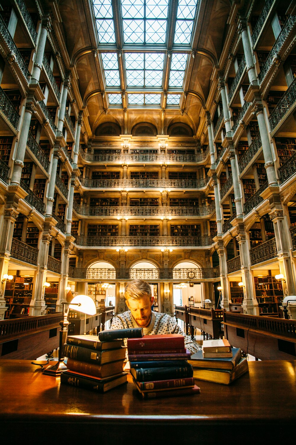 uomo seduto sulla sedia vicino alla scrivania circondato da libri