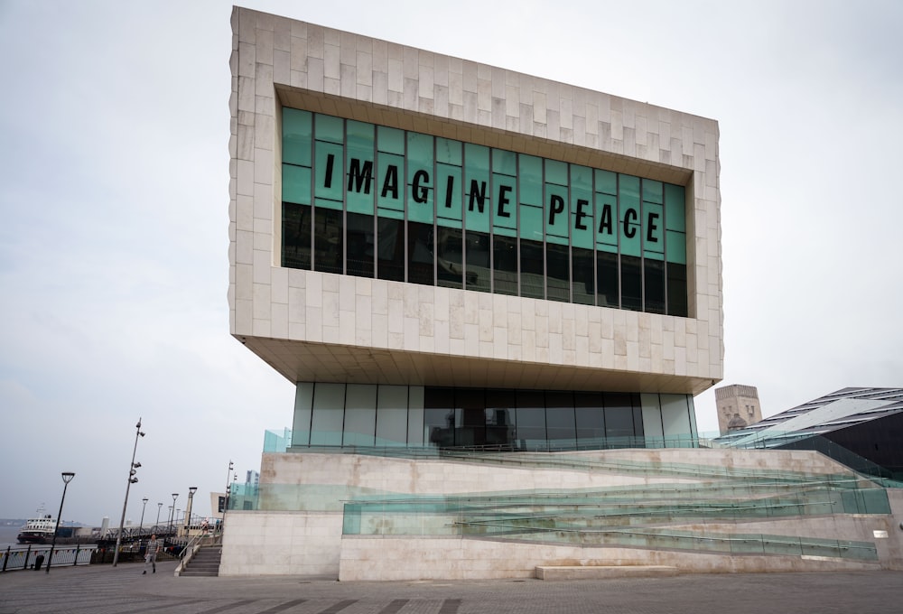 昼間の「Imagine Peace」の看板が掲げられた灰色のコンクリートの建物