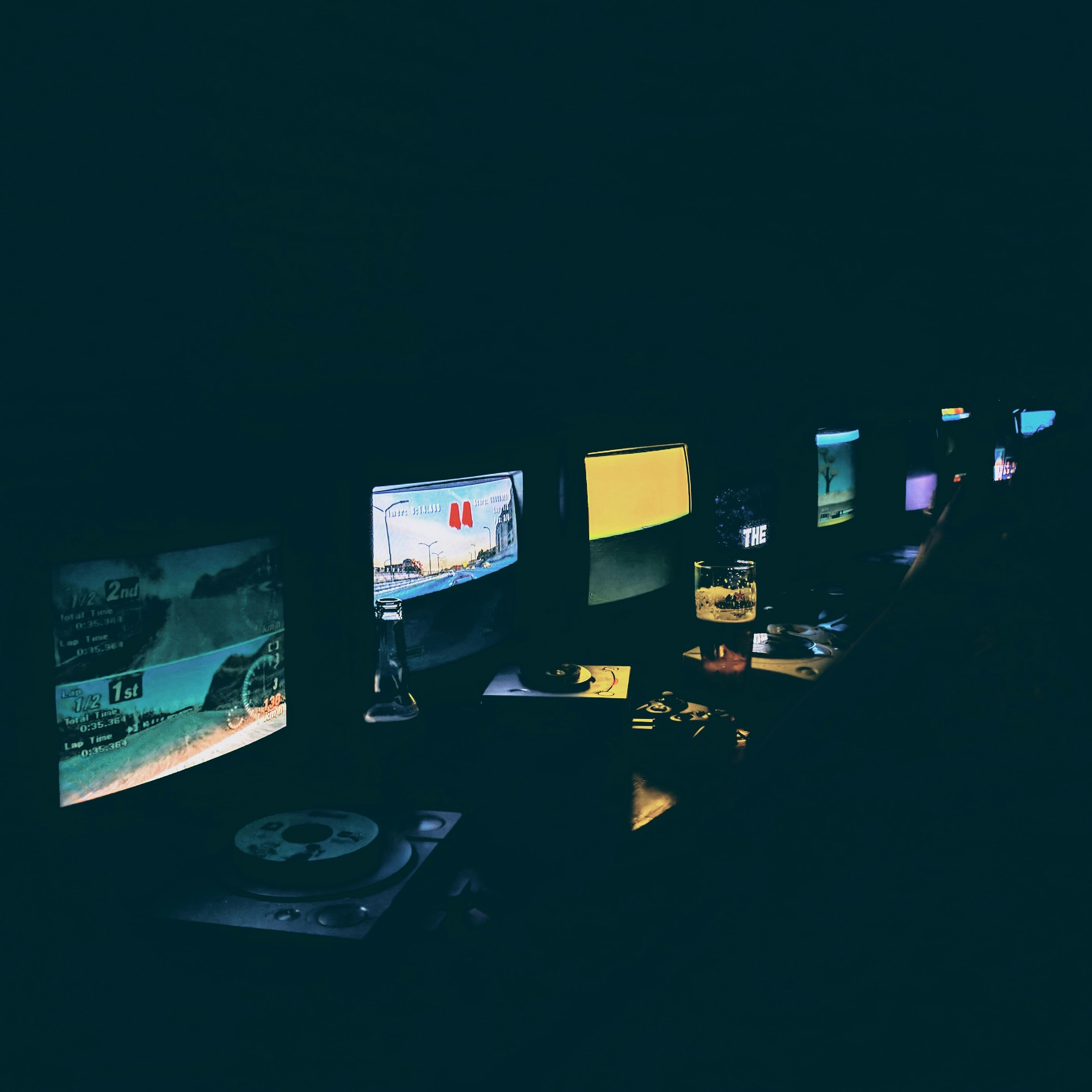 Racing simulator setup with triple screens in dark gaming room with intense neon lighting