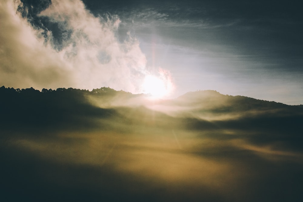 the sun is shining through the clouds over the mountains