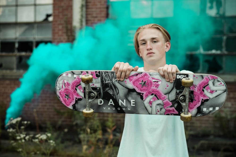 man holding gray and pink Dane skateboard