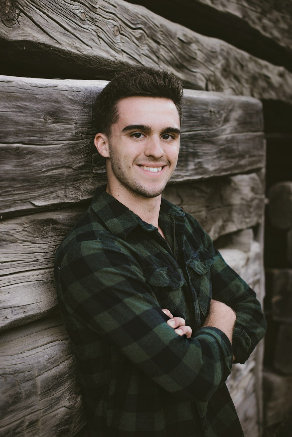 man leaning on gray wooden fence