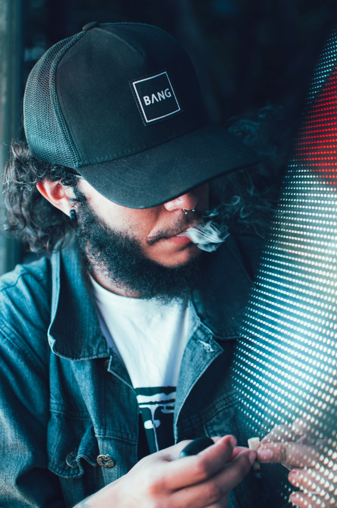 man wearing blue denim jacket and trucker hat in room