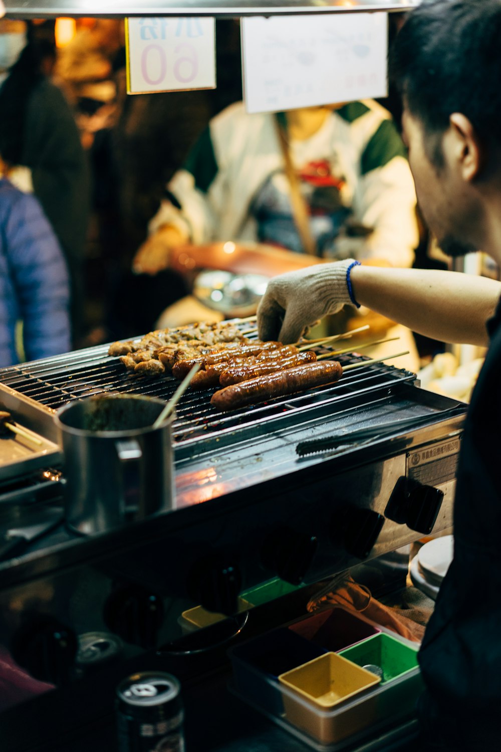 man barbecuing skewered sausages