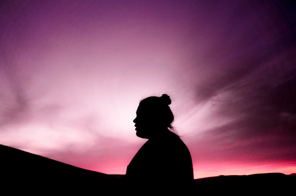 silhouette of woman under purple sky