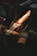 A person wearing gloves is sharpening an axe blade on a grinding wheel, with bright sparks flying off as the metal is honed.