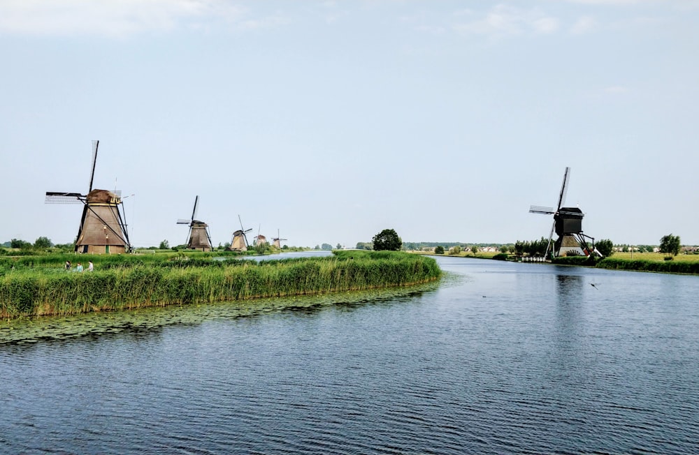 body of water beside green trees and wind mills