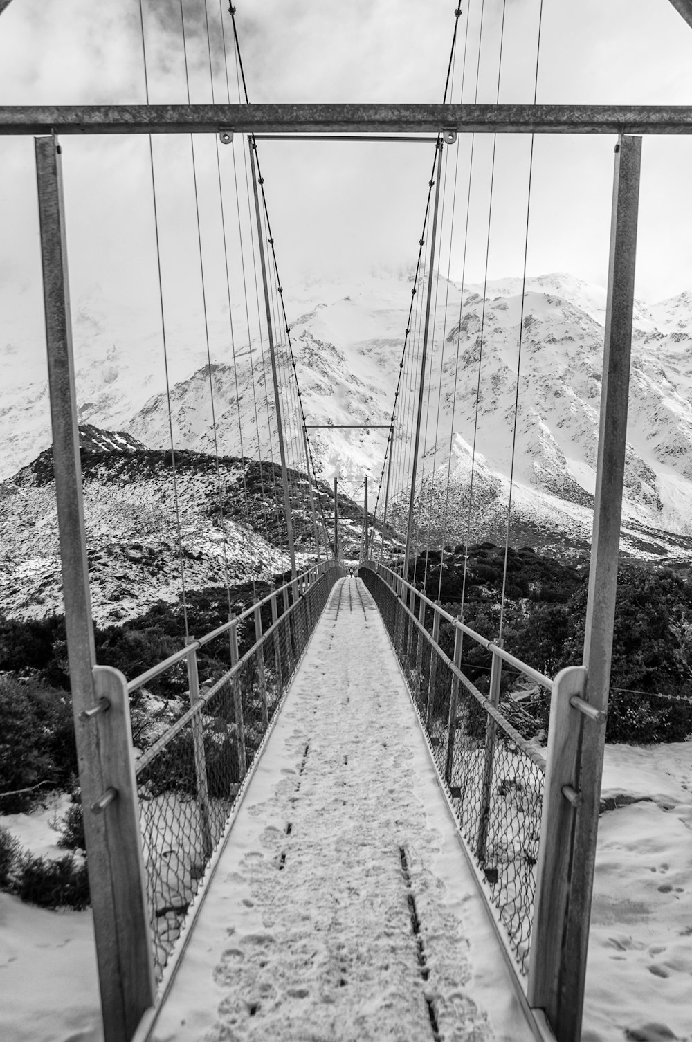 grayscale photo of bridge near mountain