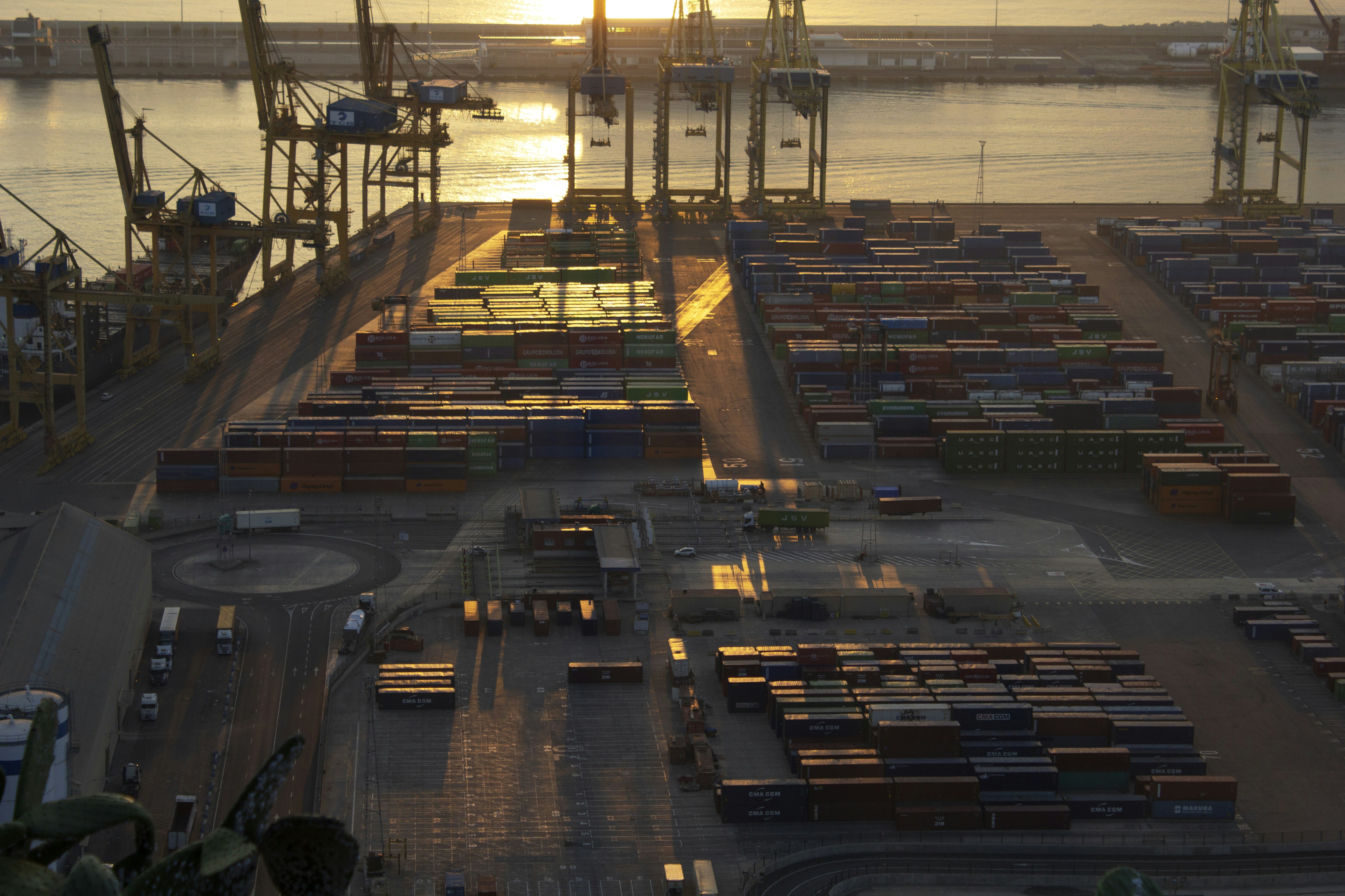 Container port at dawn — cranes over stacked shipping containers, maritime logistics