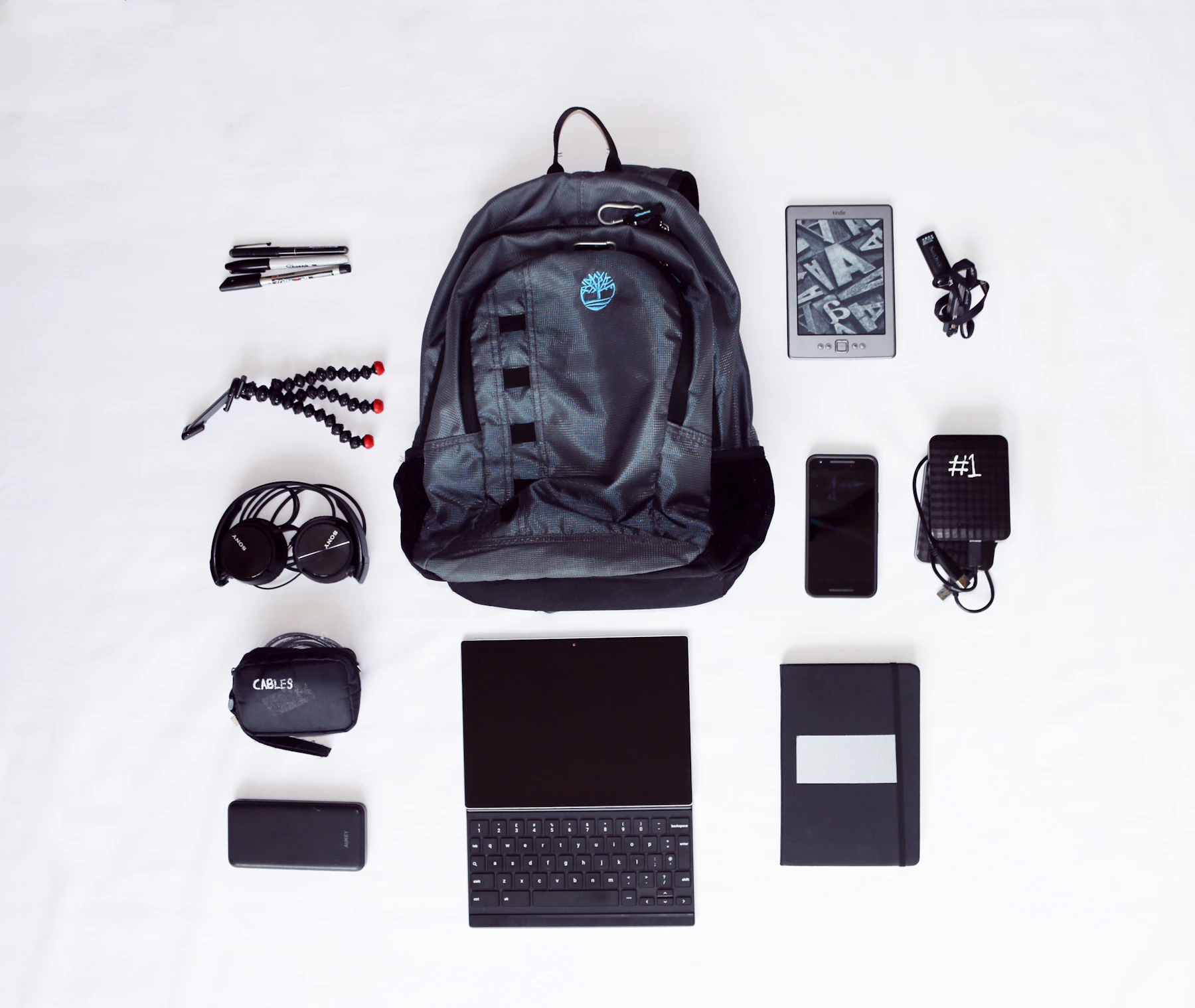 Backpack with laptop, headphones, smartphone and travel technology accessories arranged for packing