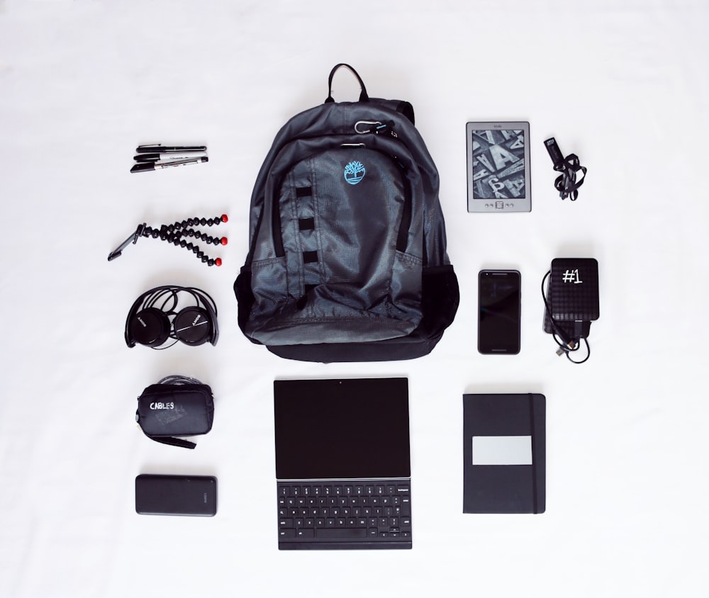 Fotografia plana de mochila, computador portátil, auscultadores, smartphone e tripé de polvo