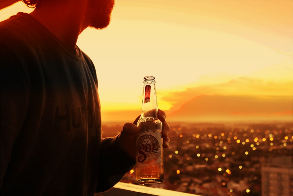 man holding bottle near buildings