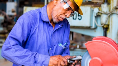 man grinding metal tool in industrial machinery