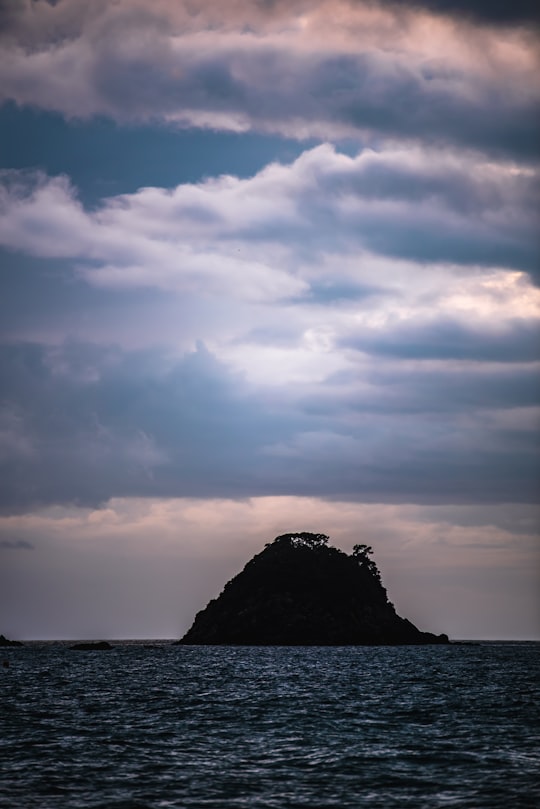 silhouette of island under cloudy sky in Hahei New Zealand