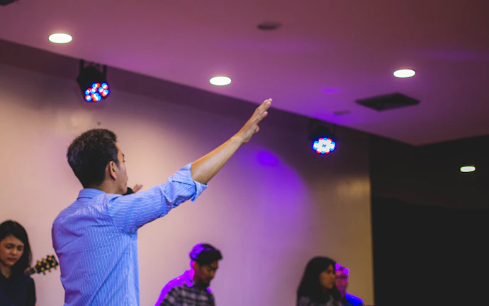 A candid moment of a speaker smiling warmly while interacting with participants in an elegant, softly lit space.