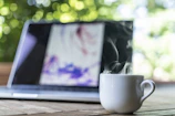 shallow focus photography of white ceramic mug near laptop
